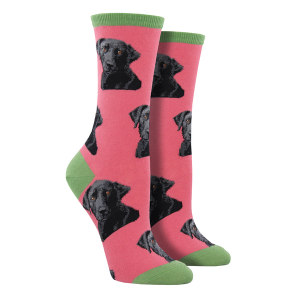 Shown on leg forms, a pair of women's fit Sock Smith cotton crew socks in pink with a green heel, toe, and cuff. These socks have realistic black labs all over the sock.