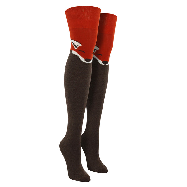 Shown on leg forms, a pair of women's Socksmith brand cotton over the knee socks in brown and orange featuring a face face design on the thigh part of the sock.
