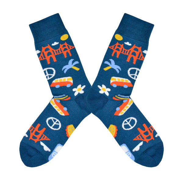 Shown in a flatlay, a pair of Yellow Owl Workshop’s navy blue nylon-cotton men's crew socks with San Francisco Golden Gate Bridge, peace sign, palm tree, daisy, VW bus and highway One sign