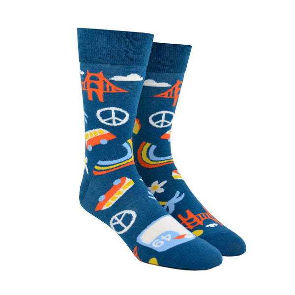 Shown on a foot form, a pair of Yellow Owl Workshop’s navy blue nylon-cotton men's crew socks with San Francisco Golden Gate Bridge, peace sign, palm tree, daisy, VW bus and highway One sign