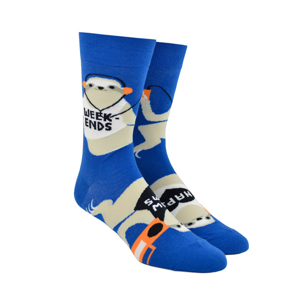 Shown on a foot form, a pair of Yellow Owl Workshop’s royal blue nylon-cotton men's crew socks with large sloths listening to music, holding boomboxes and wearing shirts that say “Sloth Life,” “Naps,” “Slow Jams” or “Weekends”