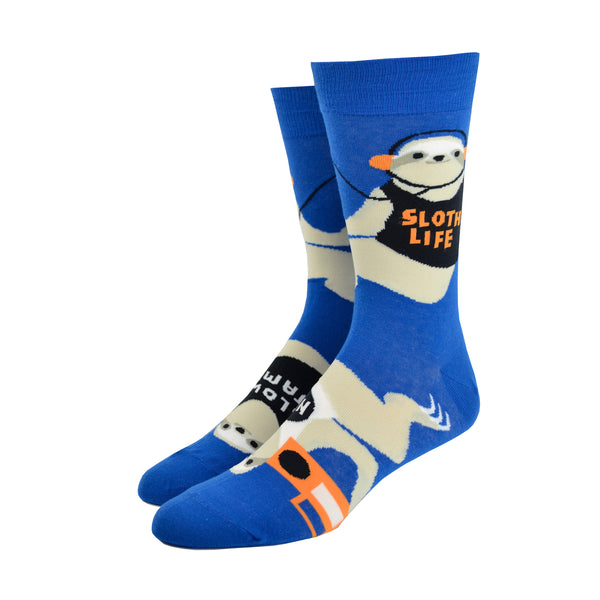 Shown on a foot form from a different angle, a pair of Yellow Owl Workshop’s royal blue nylon-cotton men's crew socks with large sloths listening to music, holding boomboxes and wearing shirts that say “Sloth Life,” “Naps,” “Slow Jams” or “Weekends”