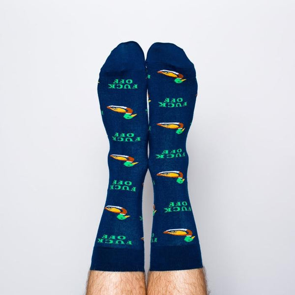 Model wearing a pair of Yellow Owl Workshop’s navy blue nylon-cotton men's crew socks with mallard duck and “Fuck Off” words in an all over pattern