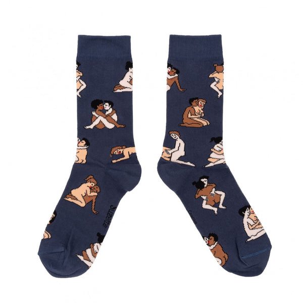 Shown in a flatlay, a pair of navy blue socks that show an interracial straight couple in various sexual positions from the Kama Sutra all over the sock.