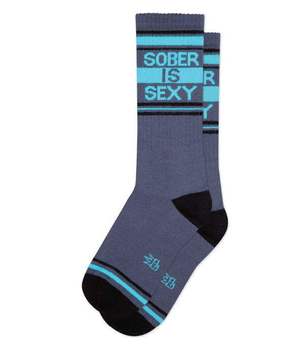 A flatlay of gray socks with black toe and heel with turquoise text that reads "sober is sexy"
